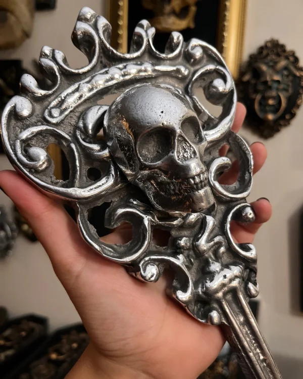 Cuchara decorativa en plata con diseño de calavera y detalles ornamentales, ideal para un toque oscuro y elegante.
