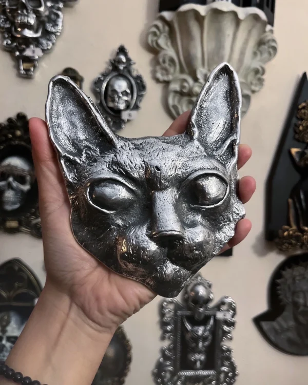 Máscara de gato hecha a mano en un acabado metálico brillante, perfecta para decoración sofisticada y oscura.