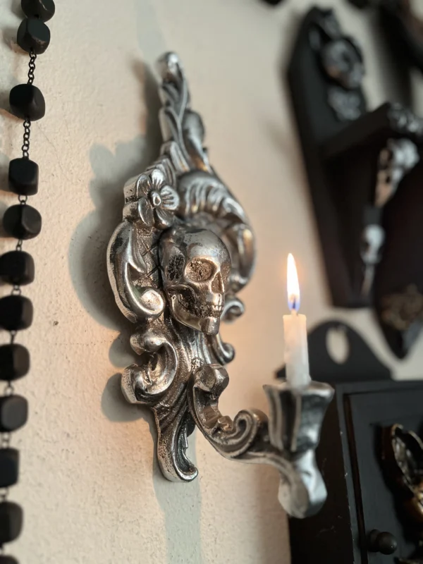 Candelabro artesanal en plata envejecida con diseño de calavera y flores, ideal para una decoración oscura y sofisticada.