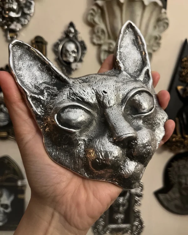 Máscara de gato artesanal en metal, con acabados en plata, perfecta para decoración sofisticada.