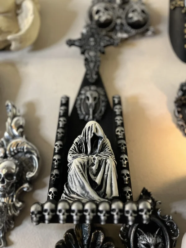 Escultura de murciélago en color negro y gris, con detalles góticos que evocan un ambiente misterioso.