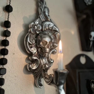 Aplique de pared en tono plateado con diseño de calavera, ideal para decoración oscura y sofisticada.