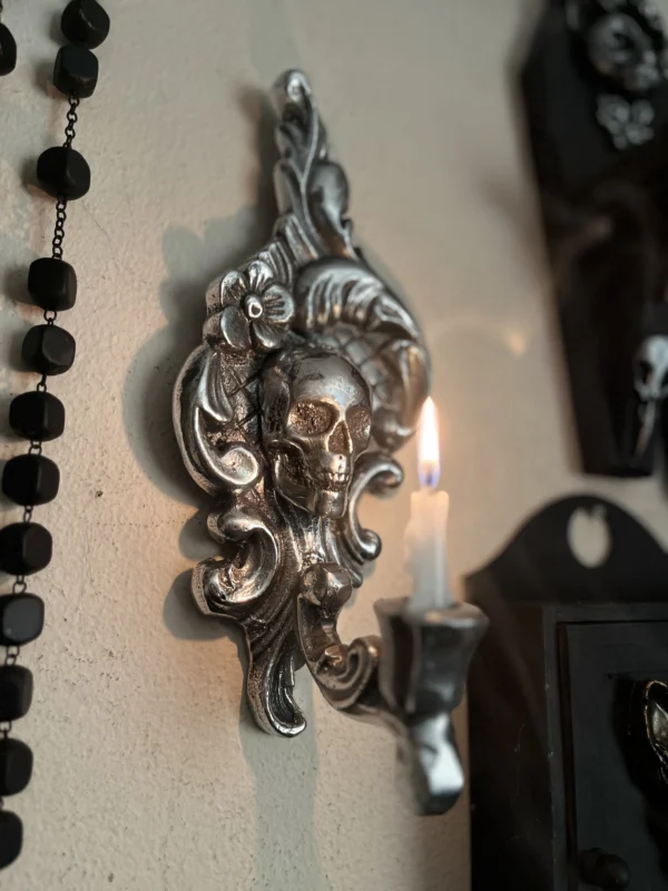 Aplique de pared en tono plateado con diseño de calavera, ideal para decoración oscura y sofisticada.